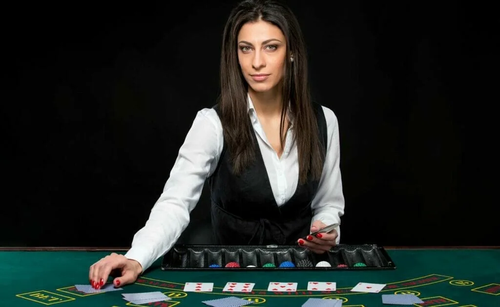Dealer memandu permainan di meja live dengan panel taruhan dan tampilan kamera